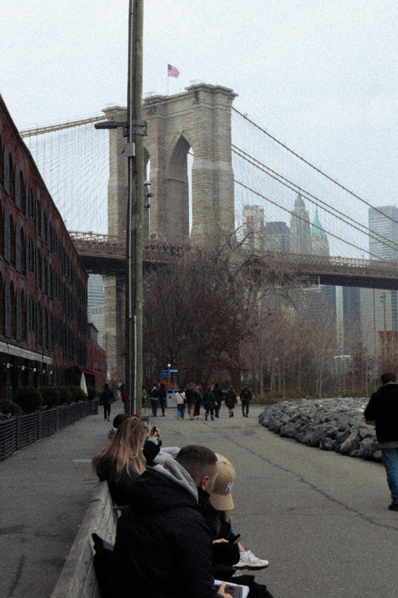 Scenic view of Brooklyn Bridge with people walking in autumn, NYC landmark.